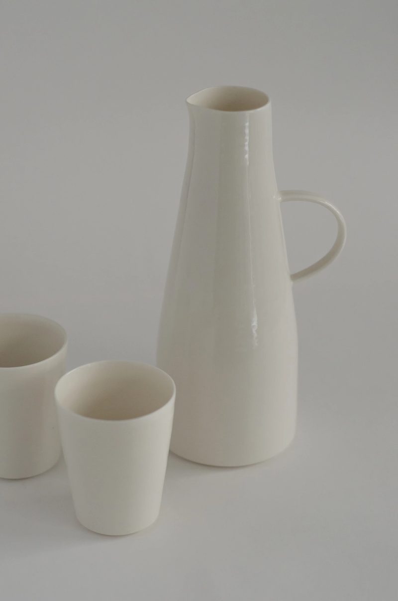 A porcelain jug and beaker against a pale background