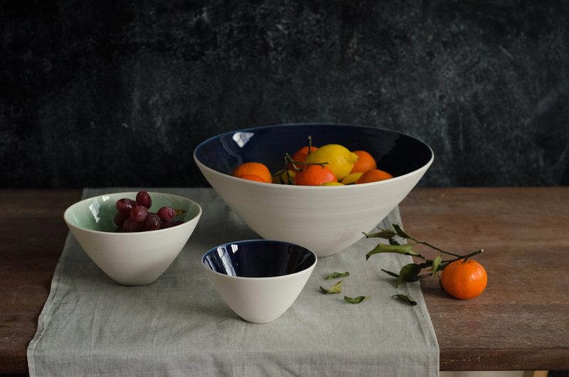 Porcelain serving bowls with fruit and cherries on a linen runner