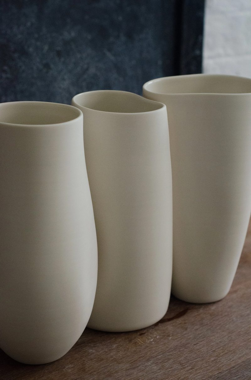 Three tall porcelain vases grouped on a wooden surface