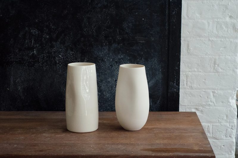 A tall porcelain vase beside a rounded vessel