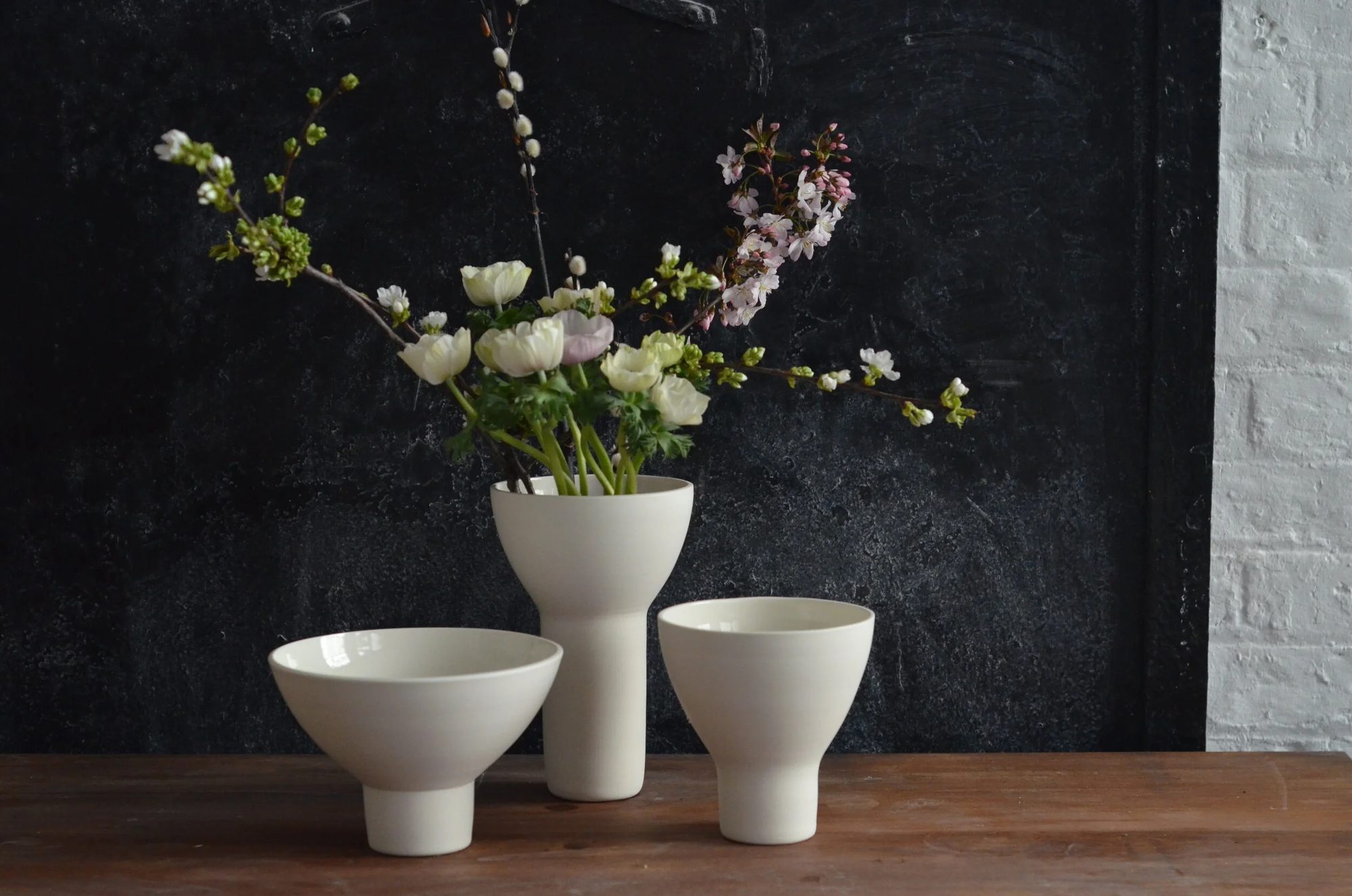 Ben Sutton porcelain vases and bowls with spring blossom against a dark backdrop